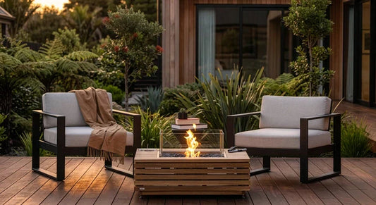 Modern outdoor fire pit table with a glass wind guard on a NZ wooden deck.