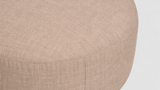 Close-up of a beige ottoman with a textured surface on a light gray background