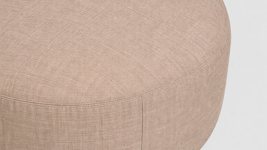 Close-up of a beige ottoman with a textured surface on a light gray background