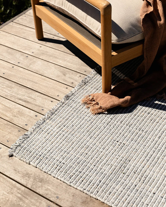 Rhodes Outdoor Floor Rug in Slate styled in a covered outdoor living space